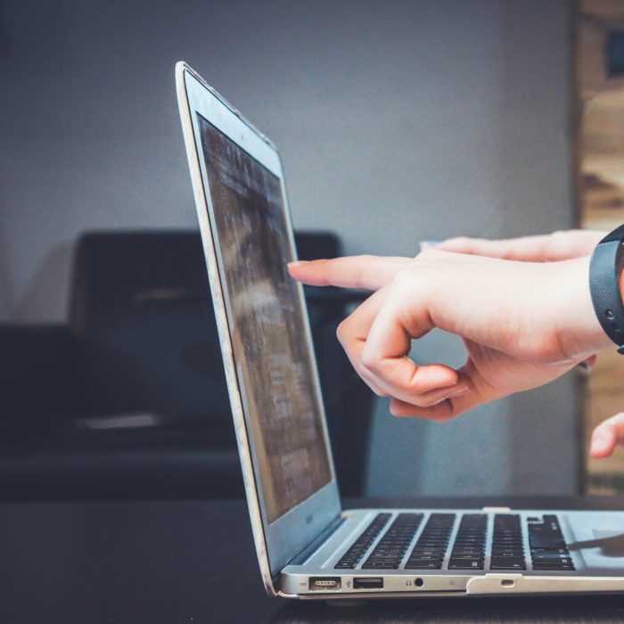 Close up of hands pointing at a laptop screen