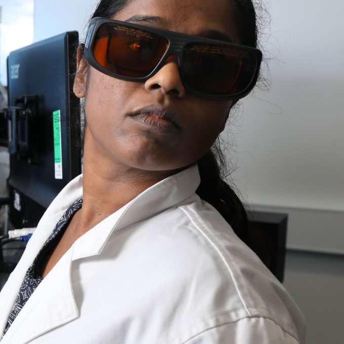 A lab technician working with physics equipment