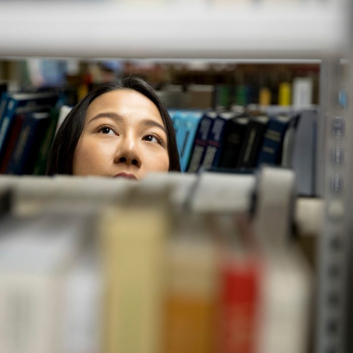 Student looking through library book shelves