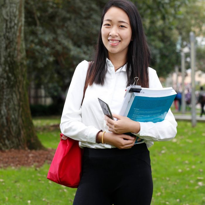 Female student holding book outside