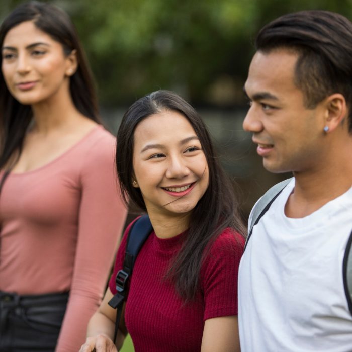 Students with backpacks walking across campus lawn