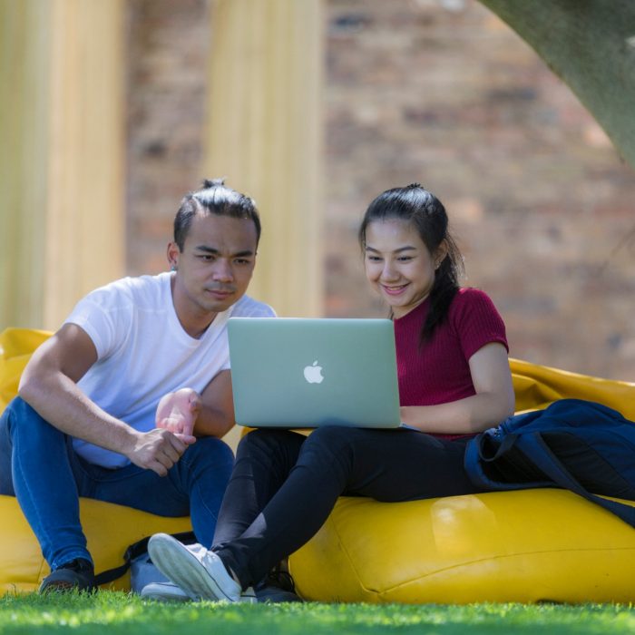 Students with laptops sitting on yellow bean bag chairs