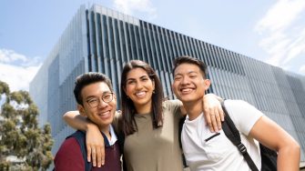 Smiling students standing in front of building