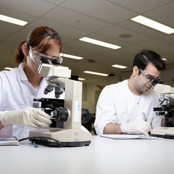 Students in Science Lab with white coat, goggles and  microscopes