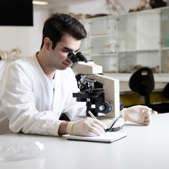 Students in Science Lab with white coat, goggles and  microscopes