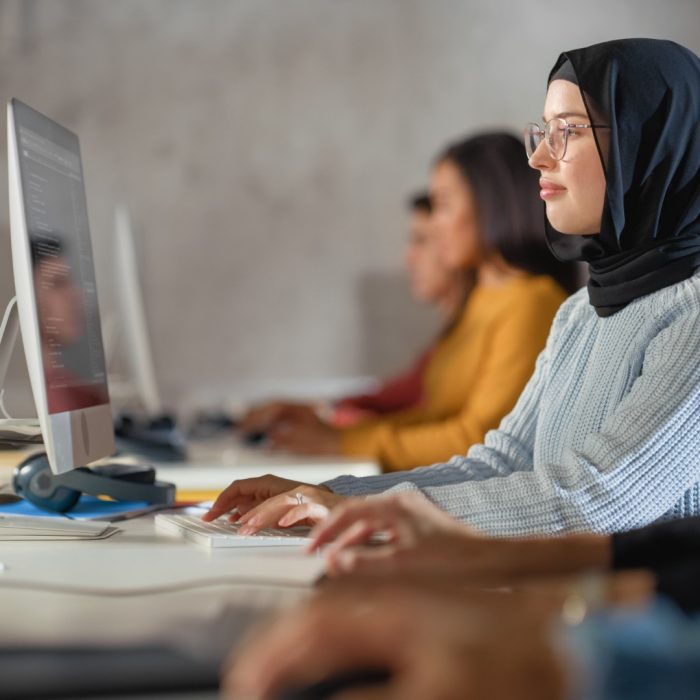 Happy Female Muslim Student Wearing a Hijab, Studying in Modern University with Diverse Multiethnic Classmates. Students Successfully Learn Computer Science, Writing Software Code.