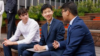Three students wearing suits sitting at the Alumni lawn in the UNSW campus 