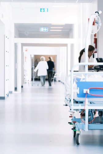 Hospital corridor with bed and patients and doctors walking
