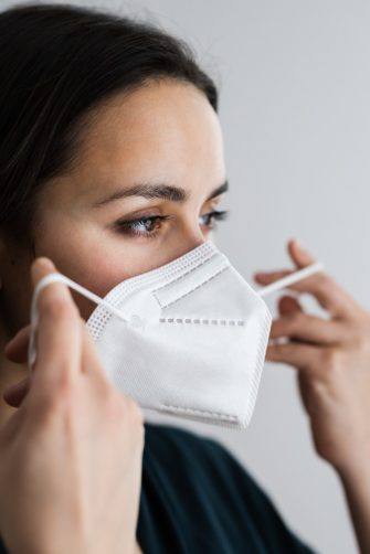 Woman putting on N95 mask