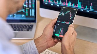 A man looks at his smartphone showing cryptocurrency fluctuations