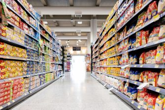 A woman reading the label on a food item while out shopping for groceries in her local supermarket.