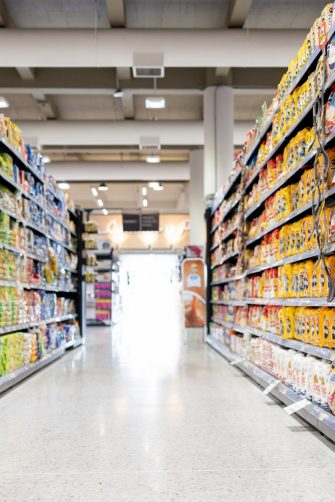 A woman reading the label on a food item while out shopping for groceries in her local supermarket.