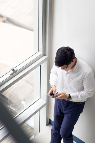 Handsome office worker hold mobile phone in hand chat with girlfriend by mobile phone at modren office balcony in relax time.