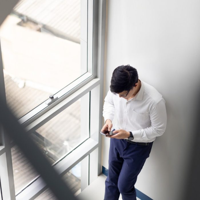 Handsome office worker hold mobile phone in hand chat with girlfriend by mobile phone at modren office balcony in relax time.