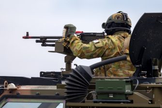 Avalon, Australia - February 27, 2015: Australian Army soldier with large machine gun in the turret of a Bushmaster armoured Personnel carrier (APC).