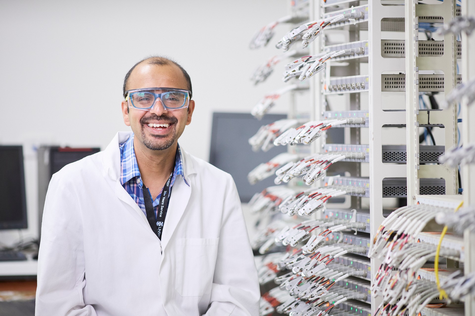 Professor Neeraj Sharma in his lab beside an array of batteries being charged