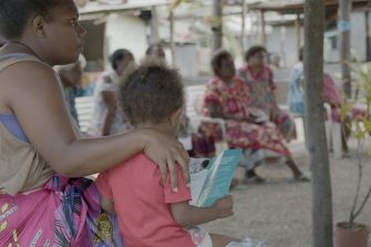 A woman with a child looking at someone speak