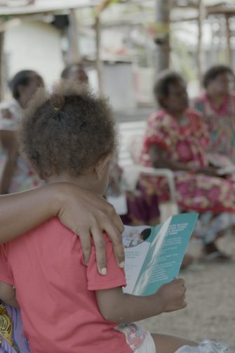 A woman with a child looking at someone speak