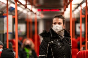 a woman wears a mask on a tram
