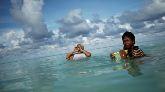 FUNAFUTI, TUVALU - NOVEMBER 28: Suega Apelu (C) calls out to a family member as Tina Makiti looks on as they swim in the lagoon on November 28, 2019 in Funafuti, Tuvalu. The�low-lying�South Pacific island nation�of about 11,000 people has been classified as �extremely vulnerable� to climate change by the�United Nations Development Programme.�The world�s fourth-smallest country is struggling to cope with climate change related impacts including five millimeter per year sea level rise (above the global average), tidal and wave driven flooding, storm surges, rising temperatures, saltwater intrusion and coastal erosion on its nine coral atolls and islands, the highest of which rises about 15 feet above sea level. In addition, the severity of cyclones and droughts in the Pacific Island region are forecast to increase due to global warming. Some scientists have predicted that Tuvalu could become inundated and uninhabitable in 50 to 100 years or less if sea level rise continues.�The country is working toward a goal of 100 percent renewable power generation by 2025 in an effort to curb pollution and set an example for larger nations. Tuvalu is also exploring a plan to build an artificial island.  (Photo by Mario Tama/Getty Images)