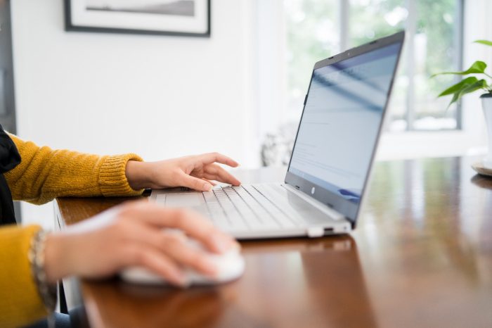 Confident young woman wearing yellow top and working from her brightly lit modern home in Auckland, New Zealand.