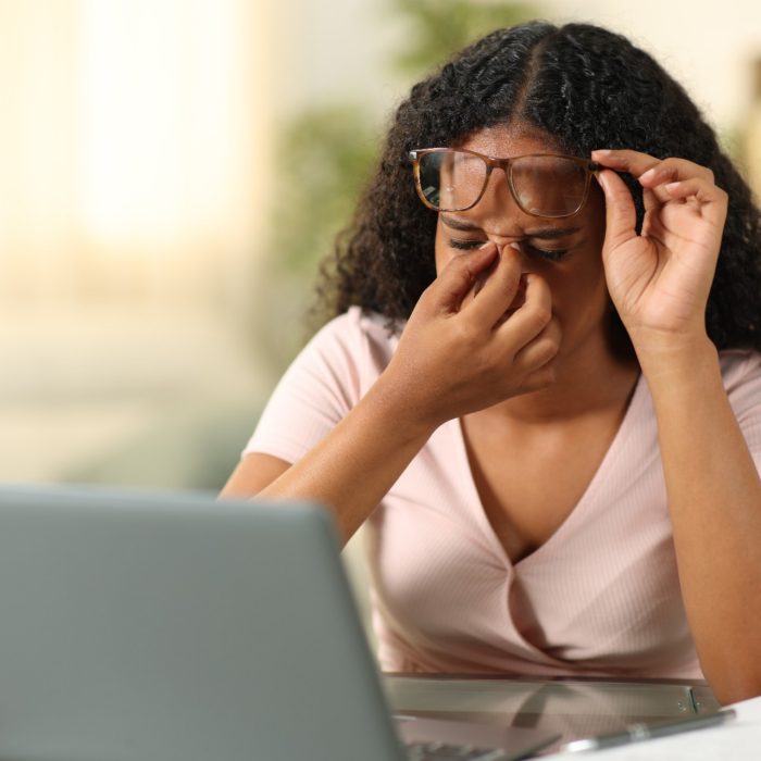 Black student suffering eyestrain studying at home