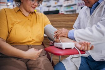 Male pharmacist measuring blood pressure to woman at the pharmacy.