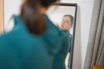 An Asian woman is looking in the mirror