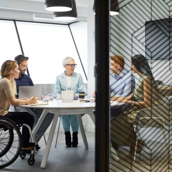 Male and female professionals discussing in board room. Disabled businesswoman communicating with coworkers in meeting. They are at office.