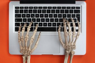 Skeleton hands typing on laptop