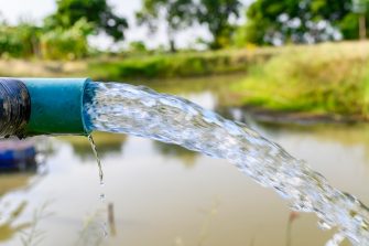 Agriculture blue pipe with groundwater gushing in pond