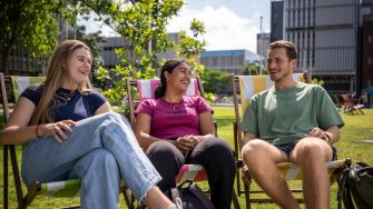 A group of students sitting on lawn chairs at the Village Green