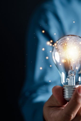 Innovation through ideas and inspiration ideas. Human hand holding light bulb to illuminate, idea of creativity and inspiration concept of sustainable business development.