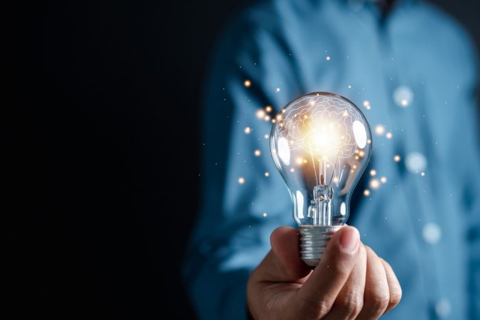 Innovation through ideas and inspiration ideas. Human hand holding light bulb to illuminate, idea of creativity and inspiration concept of sustainable business development.