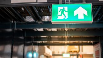 Green emergency exit sign or fire exit sign showing the way to escape with arrow symbol.