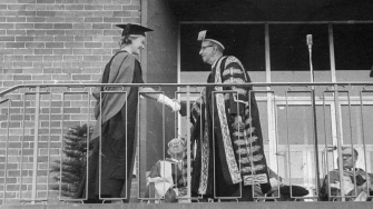 archive image of outdoor graduate ceremony handshake