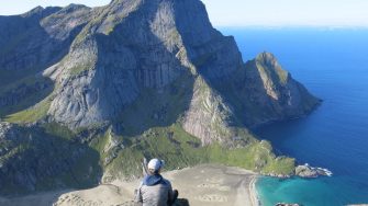 Student sitting overlooking mountains and bright blue water.