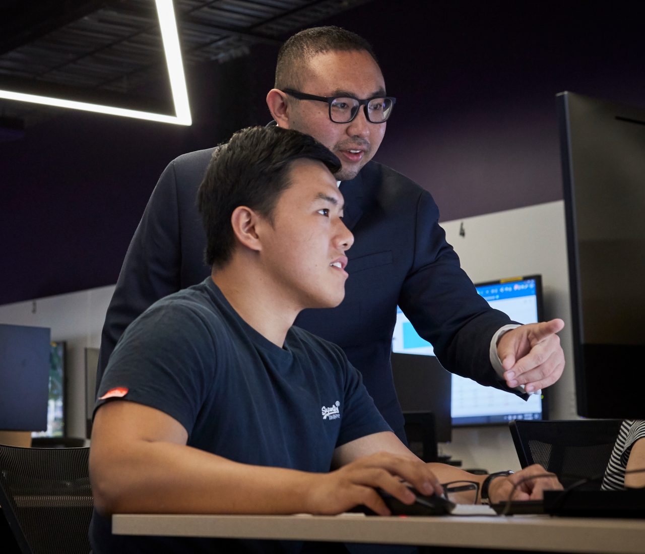 Teacher giving advice to student at computer