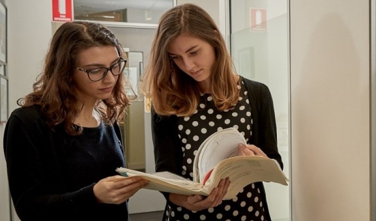 Photo of two peoplle examining documents together