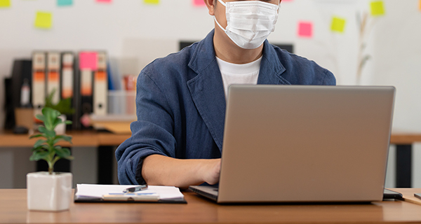 student at laptop with mask on