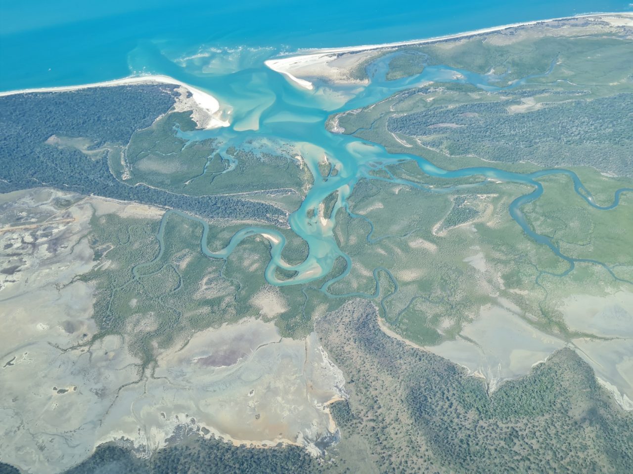 Aerial photo of intricate and beautiful patterns of aqua coloured water and white sand winding it's way inland, made from small creeks and estuaries  on the coast