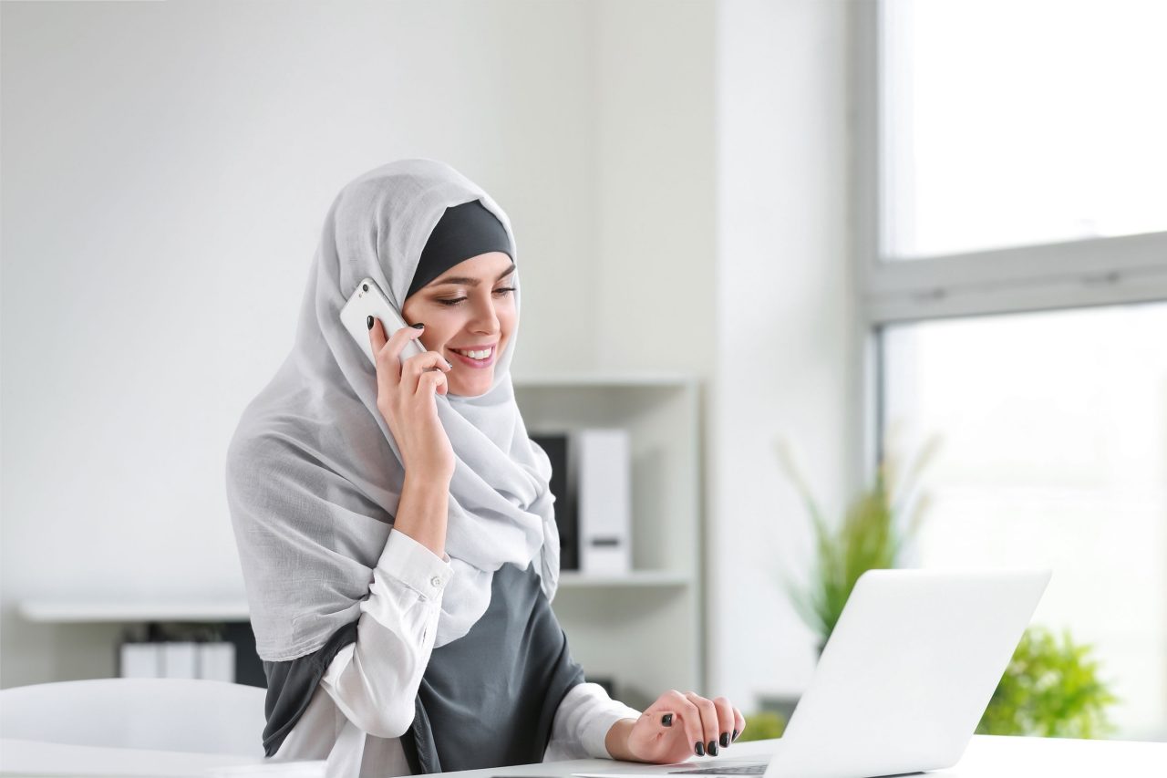 Photo of woman talking on phone at laptop