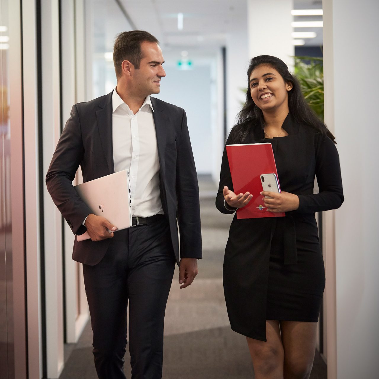 Photo of two colleagues walking together whilst chatting about their postgraduate studies